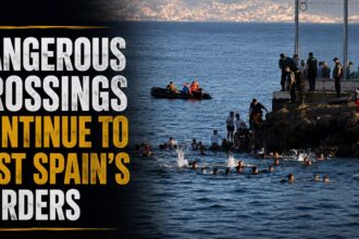 Headline banner reads 'Dangerous Crossings Continue to Test Spain's Borders' beside a sea coastline with migrants swimming near a fenced border and officials overseeing from the rocks